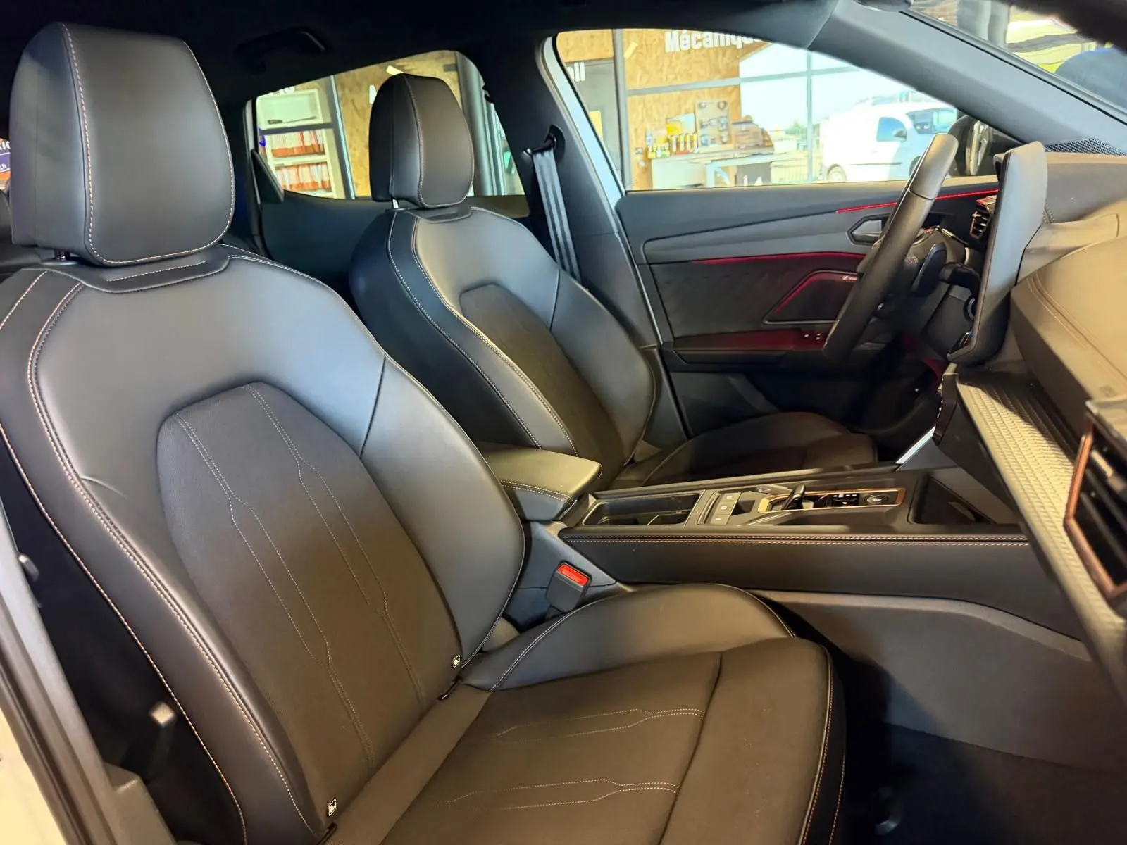 Vue intérieure côté droit du CUPRA Formentor 2025, sièges en cuir noir avec surpiqûres contrastantes et éclairage d'ambiance rouge.