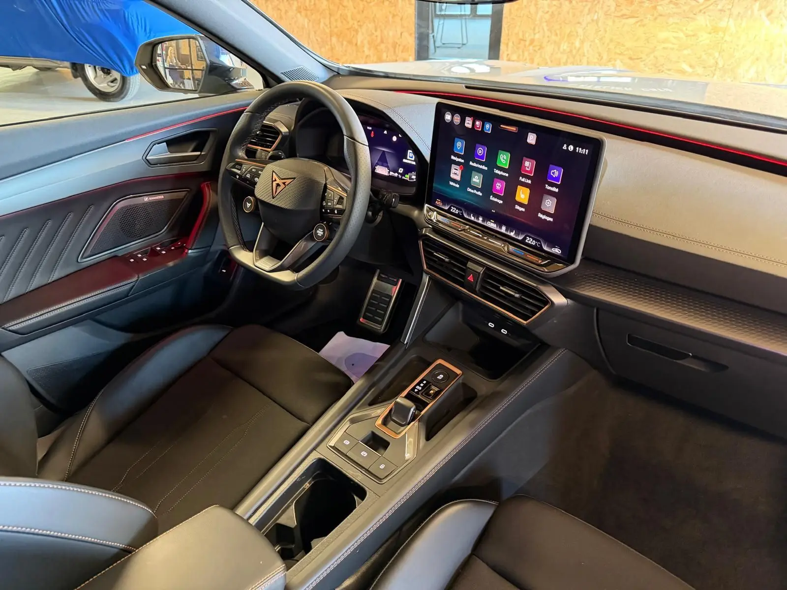 Vue intérieure côté conducteur de la CUPRA Formentor 2025, volant Supersports, écran tactile HD et finitions noires avec surpiqûres rouges.