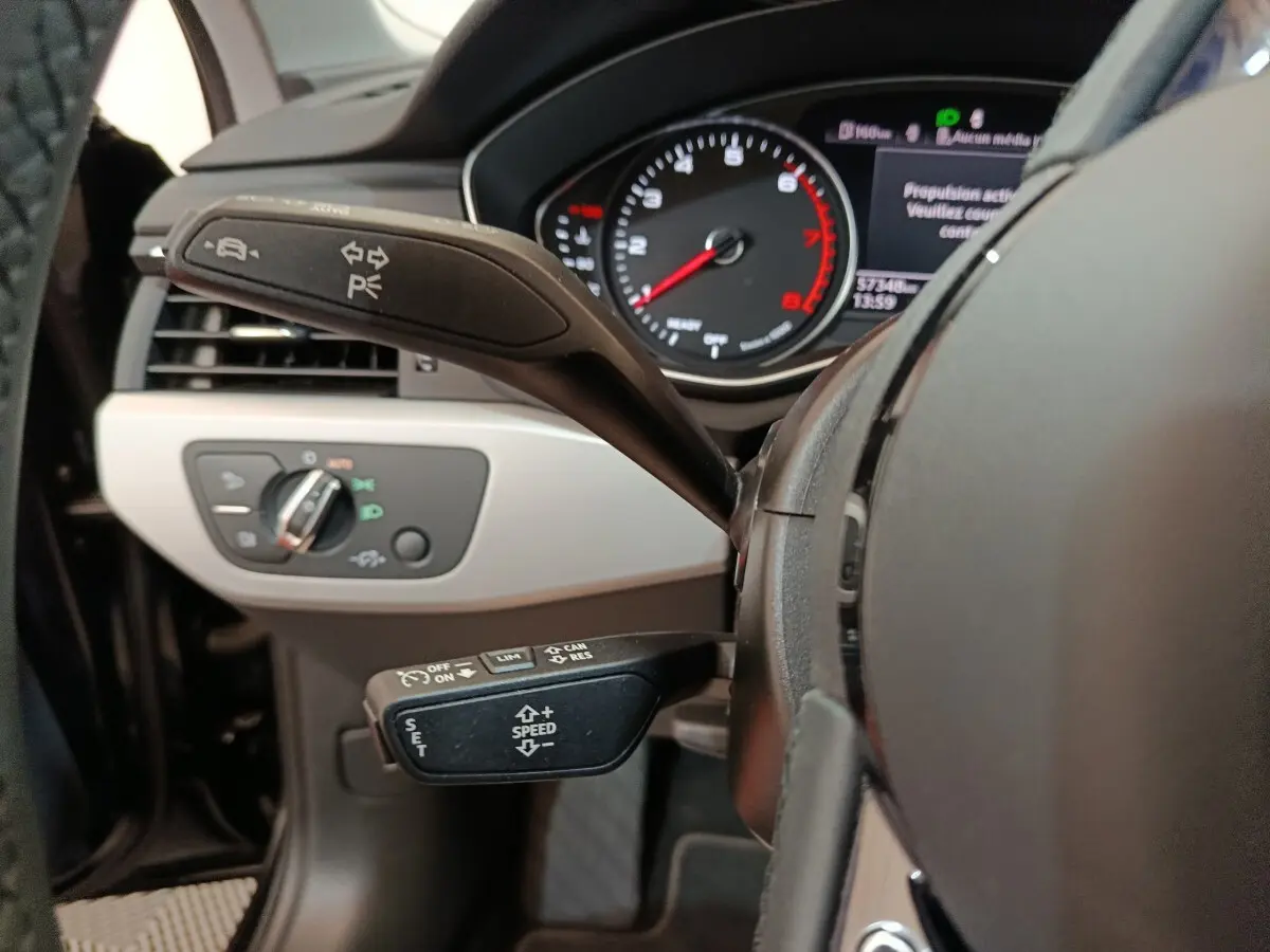 Gros plan sur le volant noir et les commandes au volant de l'Audi A4 35 TFSI 2024, avec tableau de bord digital visible.
