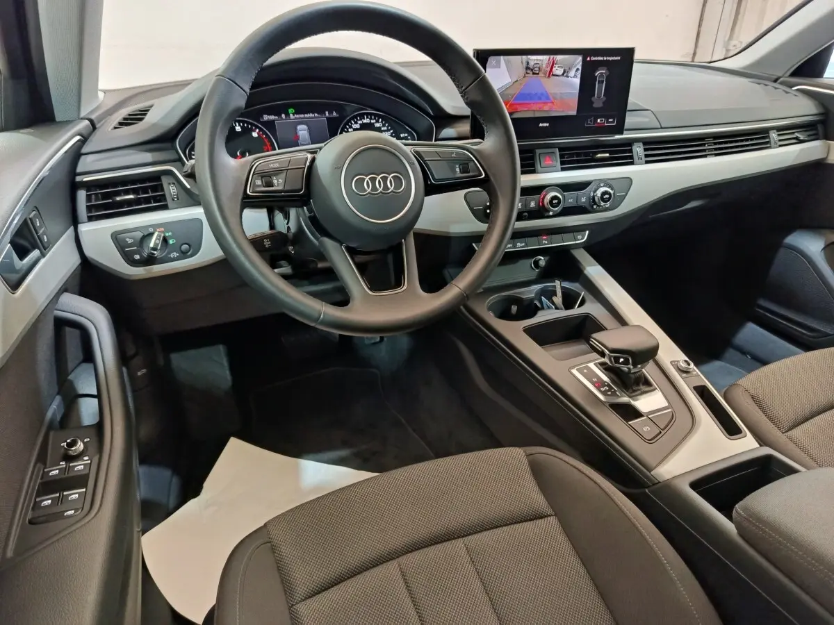 Intérieur Audi A4 35 TFSI 2024 vu côté conducteur, volant cuir, écran tactile avec caméra de recul, finition noire.
