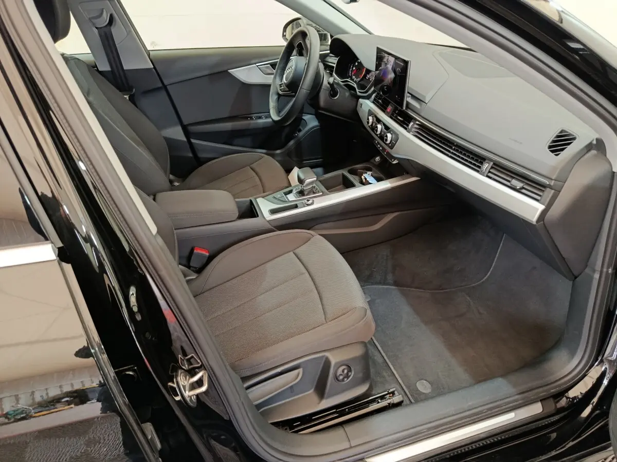 Vue intérieure côté conducteur de l'Audi A4 35 TFSI Business Line noire, avec tableau de bord moderne et sièges tissu gris.