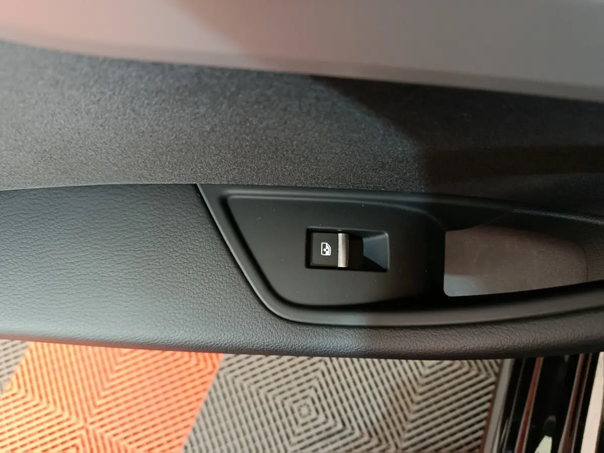 Gros plan sur le bouton de commande de vitre côté gauche dans une Audi A4 noire 2024, finition Business Line.