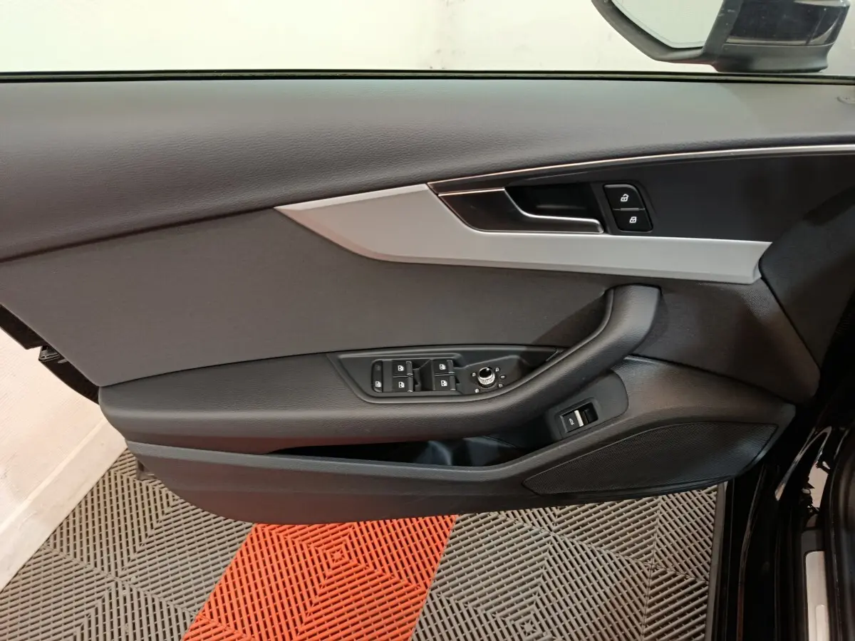 Vue intérieure côté gauche de la porte avant noire d'Audi A4 2024, avec commandes de vitres et verrouillage.