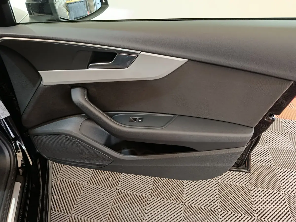 Vue rapprochée de la porte avant gauche noire de l'Audi A4 35 TFSI 2024 avec garniture grise et commande de vitre.