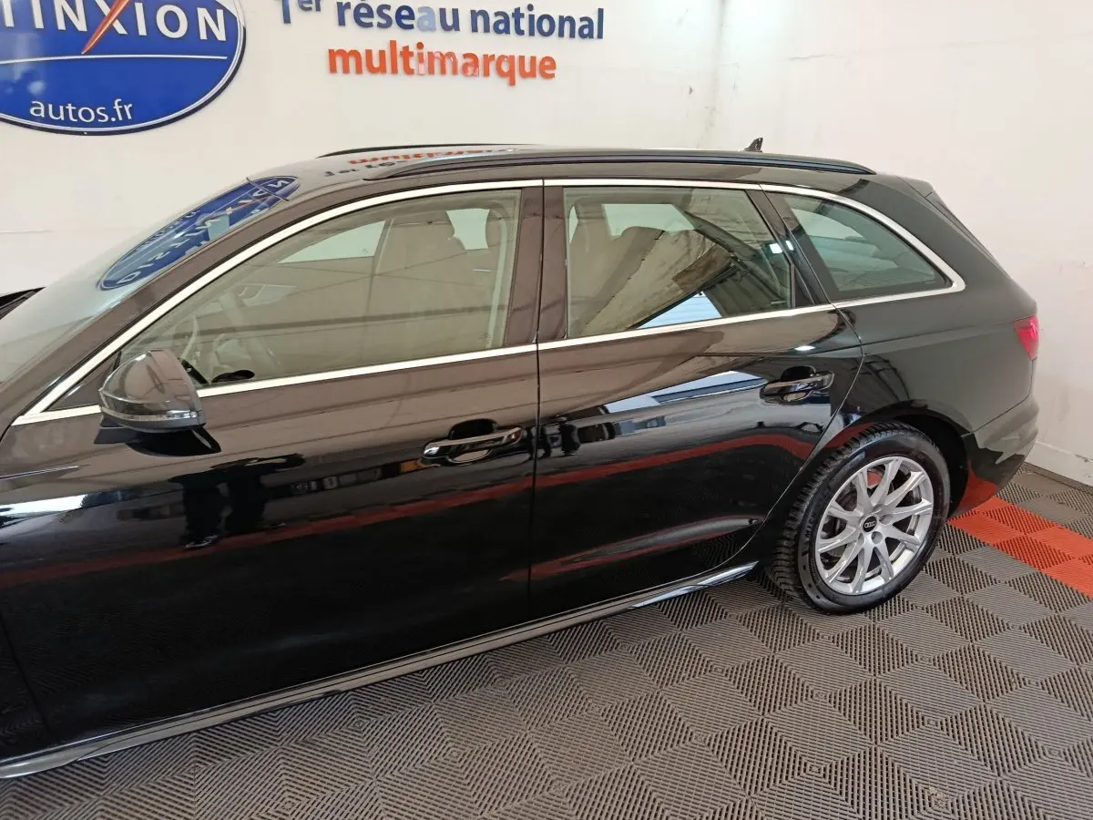 Vue latérale droite d'une Audi A4 noire 2024 break, mettant en valeur ses jantes alliage et ses vitres teintées.