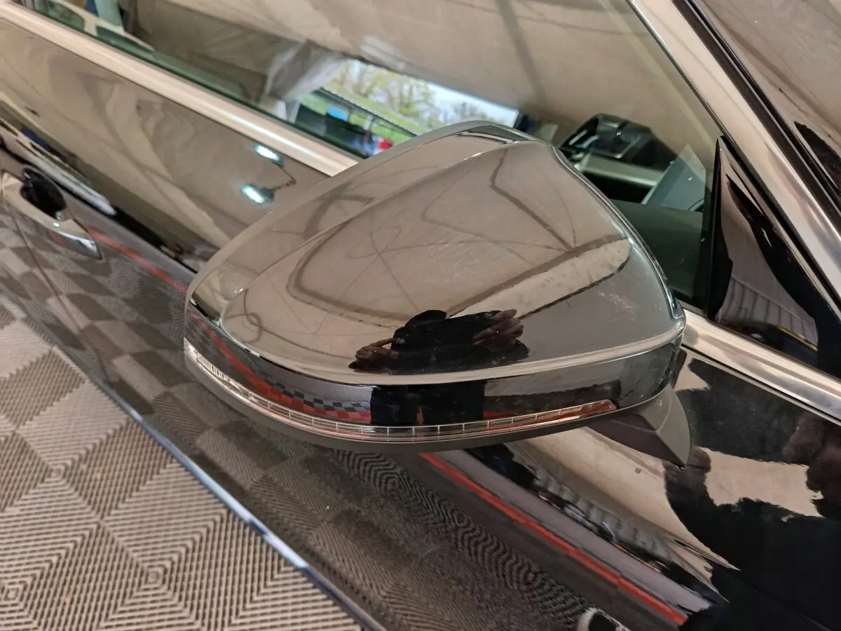 Gros plan sur le rétroviseur côté gauche noir brillant de l'Audi A4 35 TFSI 2024 avec clignotant intégré.