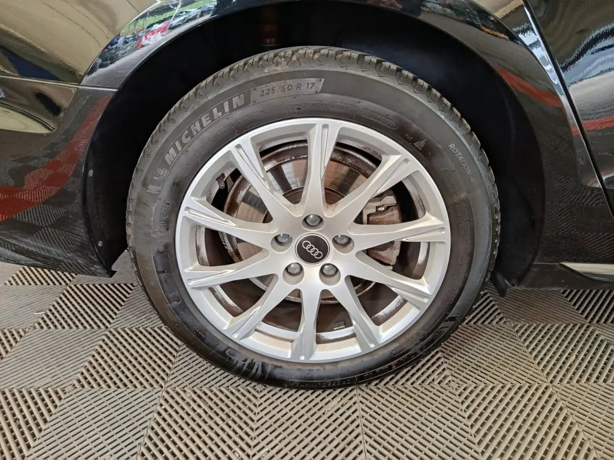 Gros plan sur la roue avant droite noire d'une Audi A4 35 TFSI 150 S tronic Business Line avec jante alliage argentée.