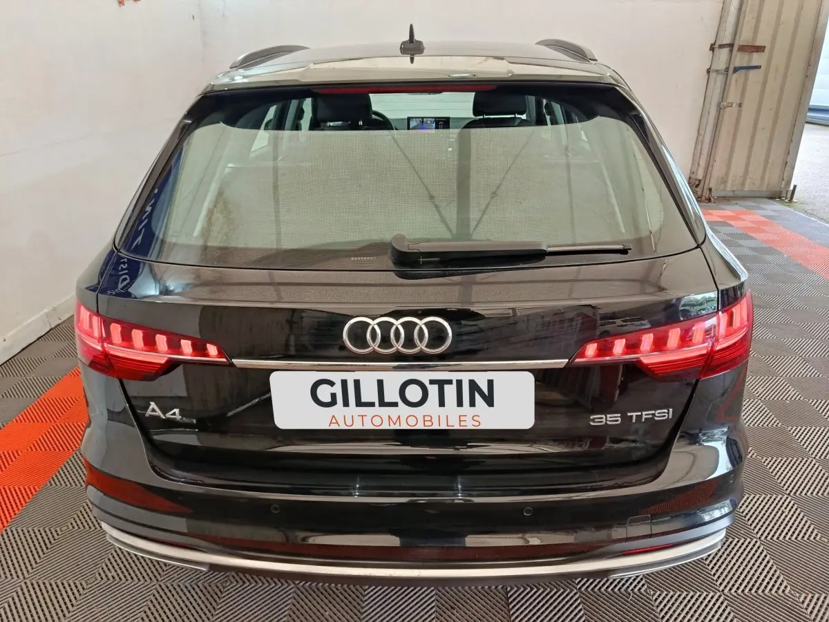 Vue arrière d'une Audi A4 35 TFSI noire, avec feux LED allumés et logo Audi bien visible.
