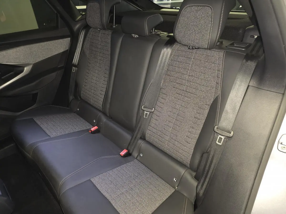 Vue intérieure du siège arrière du Peugeot 3008 gris, avec sellerie tissu et cuir noir, ceintures de sécurité et appuie-têtes visibles.