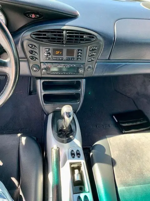 Vue intérieure centrée sur la console centrale et levier de vitesse manuelle d'une Porsche Boxster 986 gris de 2001.