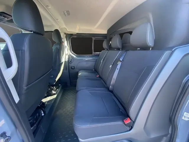 Vue intérieure côté droit du Renault Trafic cabine approfondie 2025 gris urbain, sièges arrière en tissu noir avec ceintures.