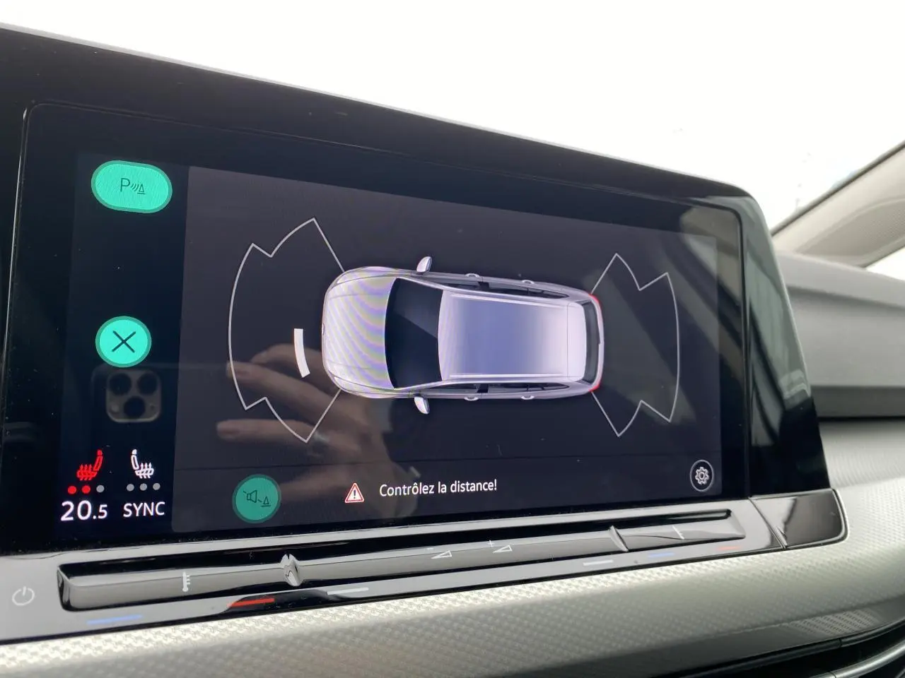 Écran tactile intérieur de la Volkswagen Golf SW 2.0 TDI montrant l'aide au stationnement avec vue aérienne du véhicule blanc oryx.