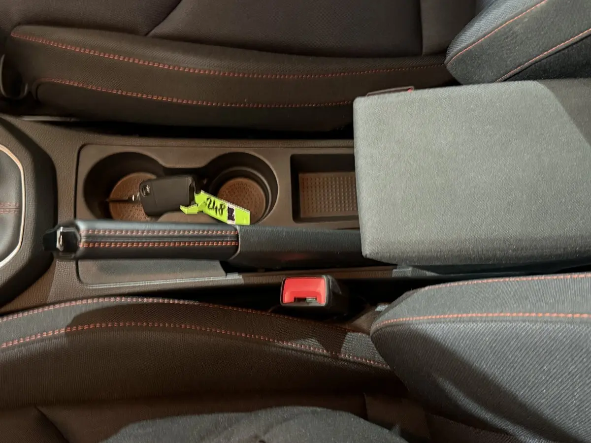 Vue plongeante sur la console centrale noire de la SEAT IBIZA 1.0 TSI 110 FR avec frein à main et clé posée.