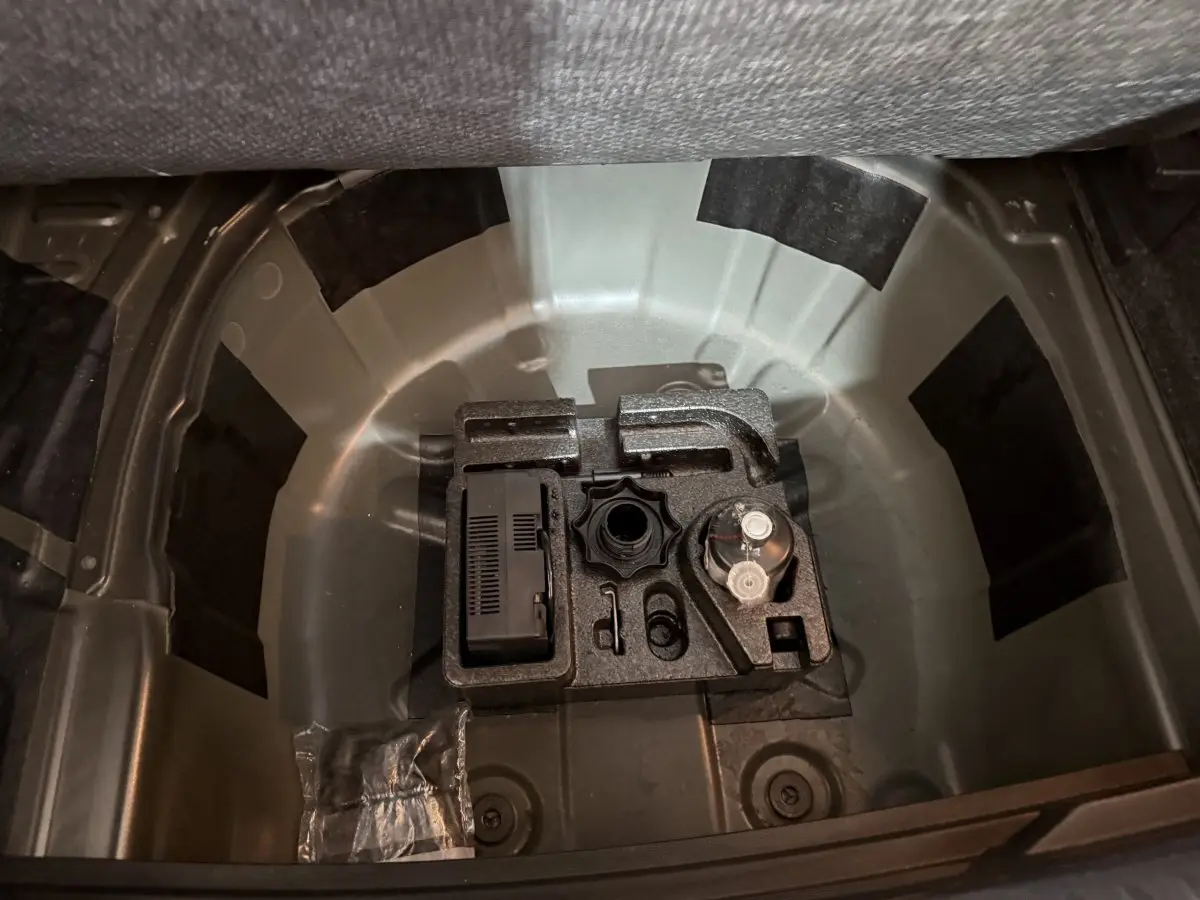 Vue plongeante sur le coffre ouvert d'une SEAT Ibiza noire 2024, montrant le rangement sous la tablette arrière.