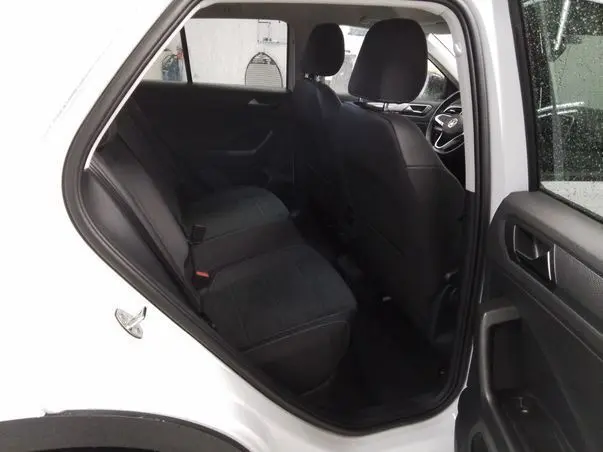 Vue intérieure côté gauche arrière du Volkswagen T-Roc blanc toit noir, montrant les sièges arrière en tissu noir.