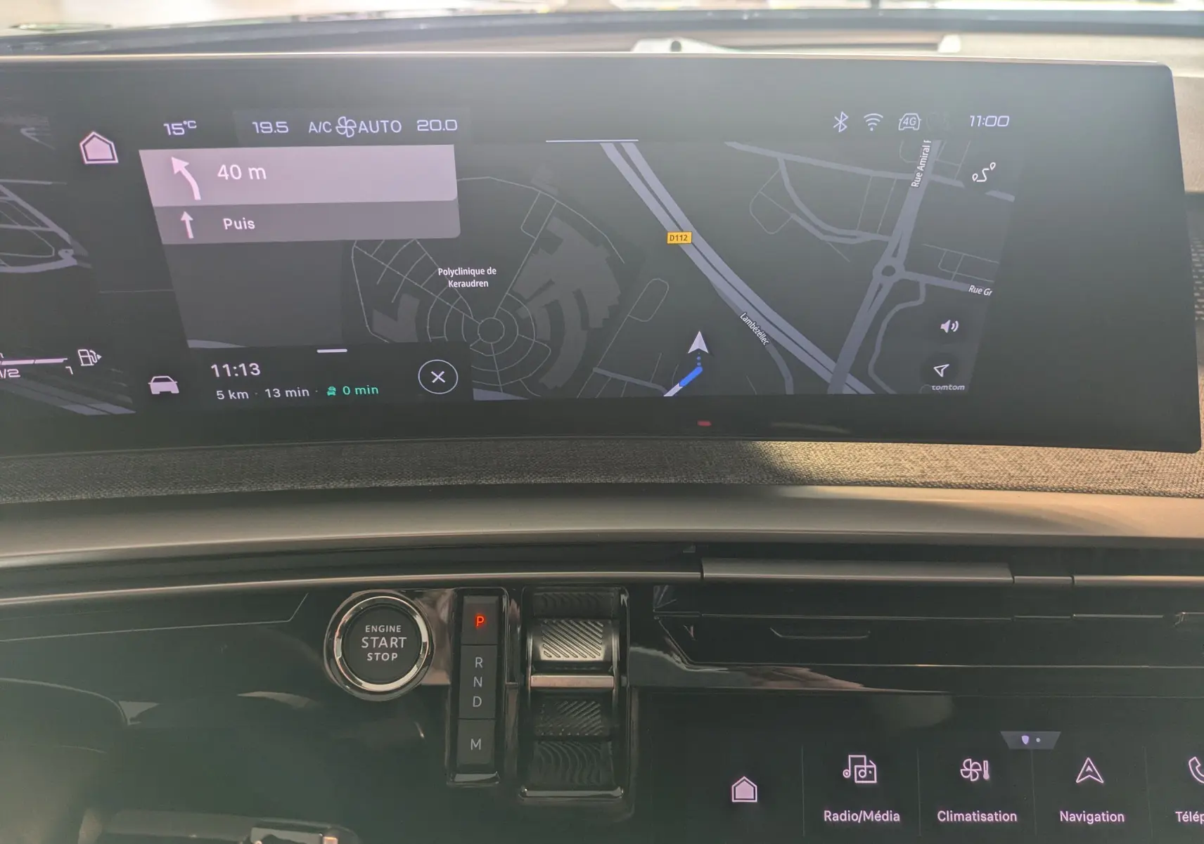 Vue intérieure du tableau de bord du Peugeot 5008 hybride 2025 avec écran tactile panoramique et navigation affichée.
