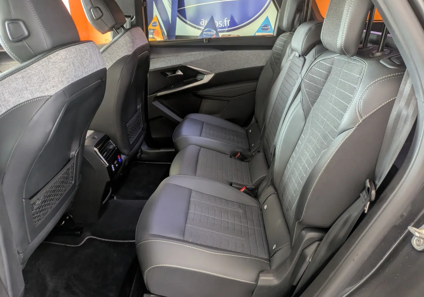 Vue latérale droite sur les sièges arrière en tissu et cuir gris du Peugeot 5008 hybride 2025 avec surpiqûres claires.