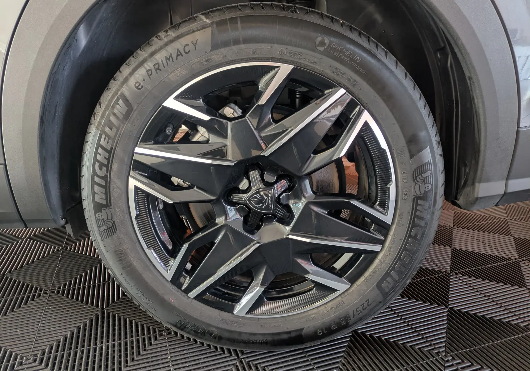 Gros plan sur la jante alliage 19’’ bicolore du côté avant droit du Peugeot 5008 Hybride gris titane.