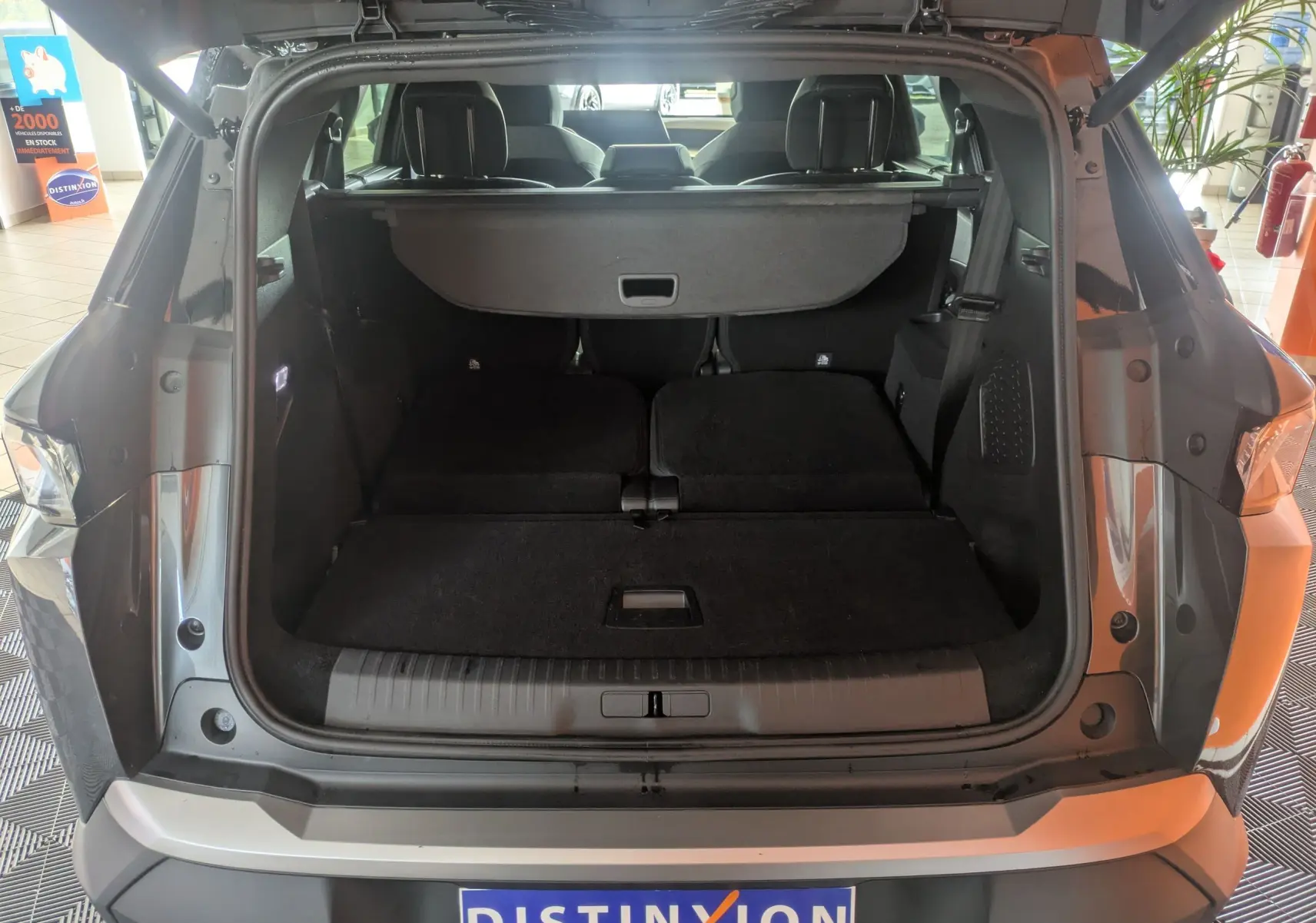 Coffre ouvert vu de l’arrière d’un Peugeot 5008 gris titane avec intérieur noir et banquette rabattue.