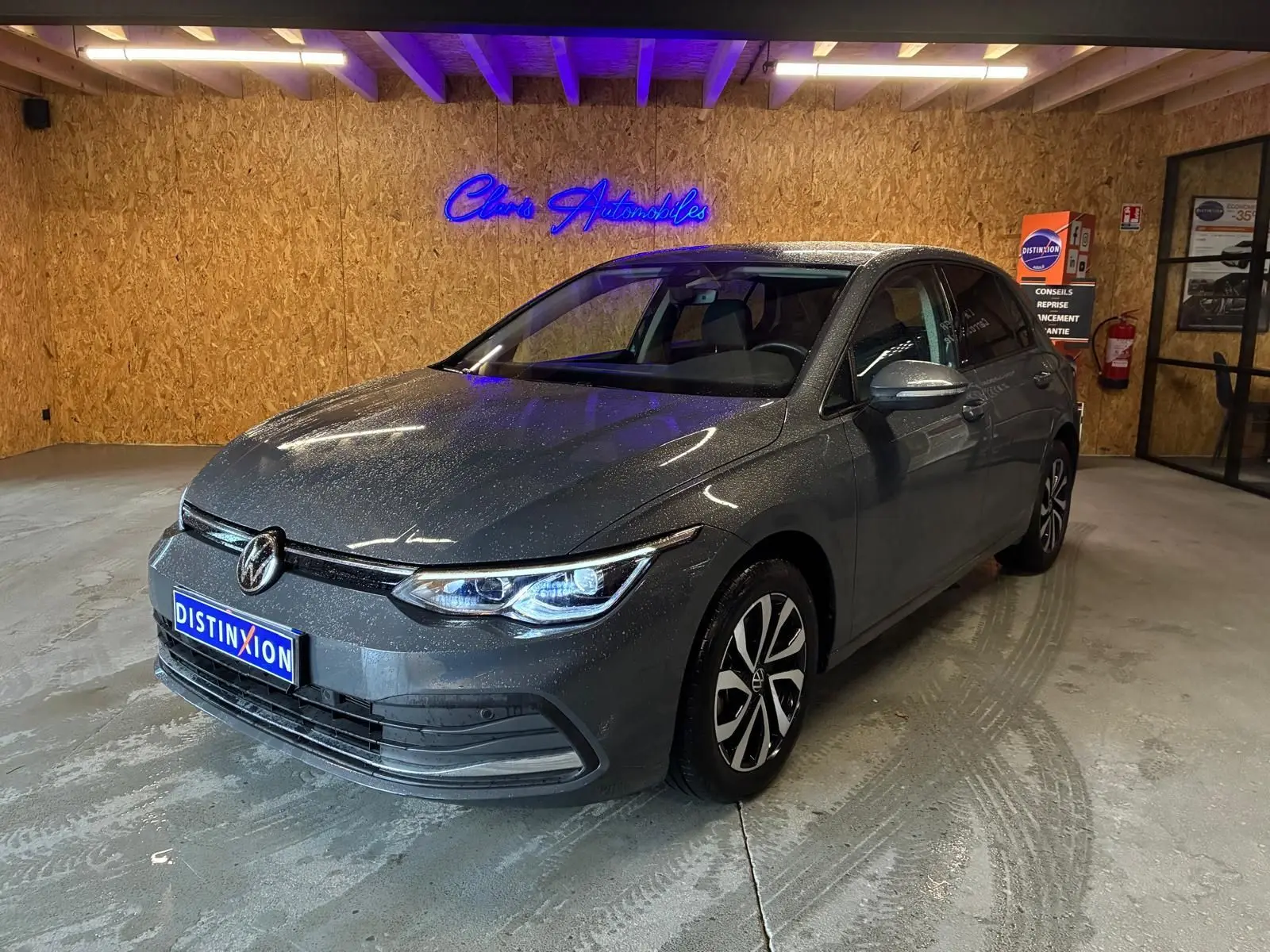 Volkswagen Golf 1.5 eTSI gris vue 3/4 avant droit dans un garage avec éclairage intérieur.