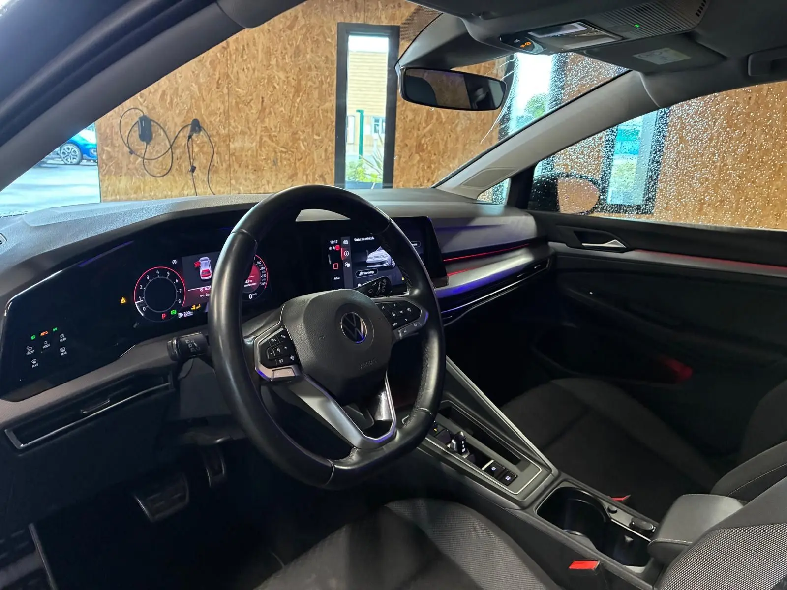Vue intérieure côté conducteur de la Volkswagen Golf 1.5 eTSI 130 DSG7 Active 2022 avec tableau de bord numérique et ambiance lumineuse rouge.
