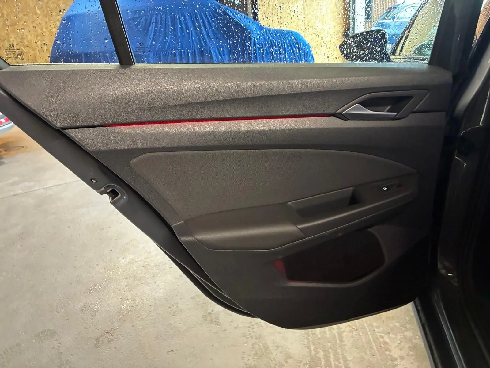 Vue intérieure de la porte arrière droite grise de la Volkswagen Golf 1.5 eTSI 130 DSG7 Active avec bande lumineuse rouge.