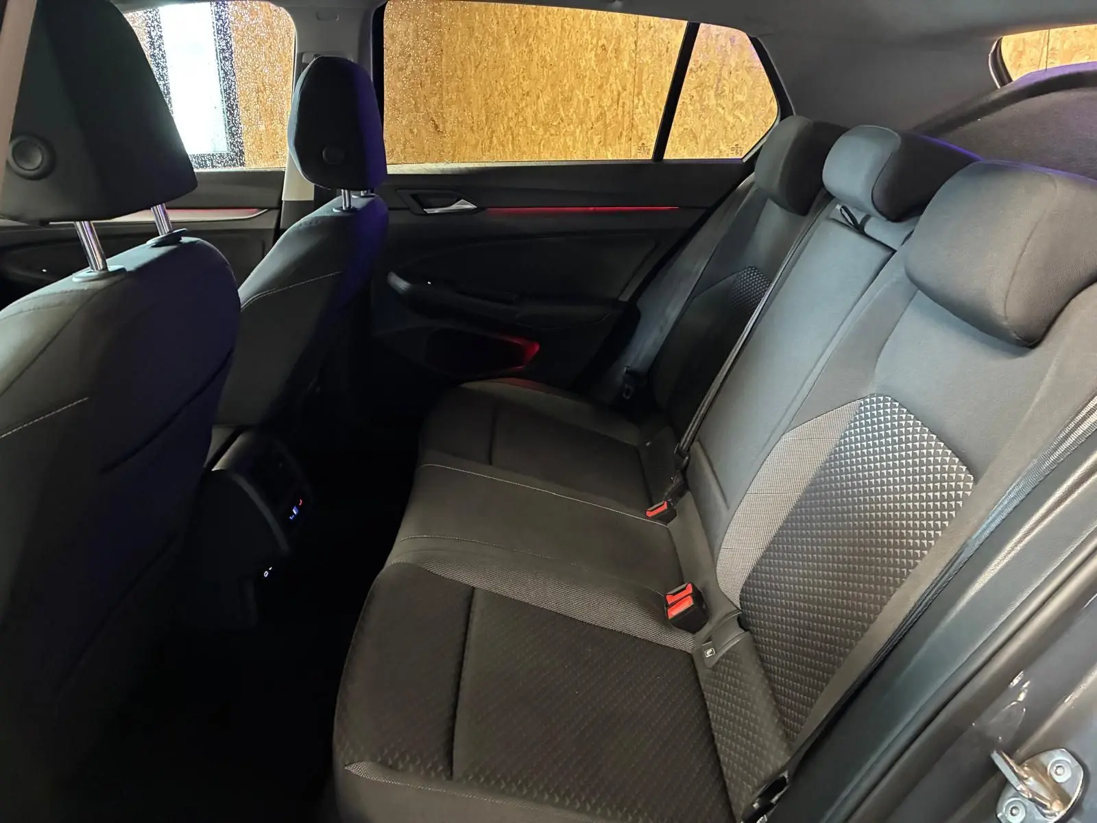 Vue intérieure arrière côté droit de la Volkswagen Golf gris, montrant les sièges arrière en tissu noir avec détails texturés.