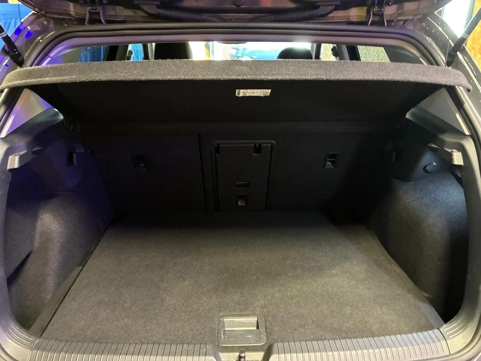 Coffre ouvert vu de l'arrière d'une Volkswagen Golf 1.5 eTSI 130 DSG7 Active, intérieur noir et tapis de coffre gris foncé.