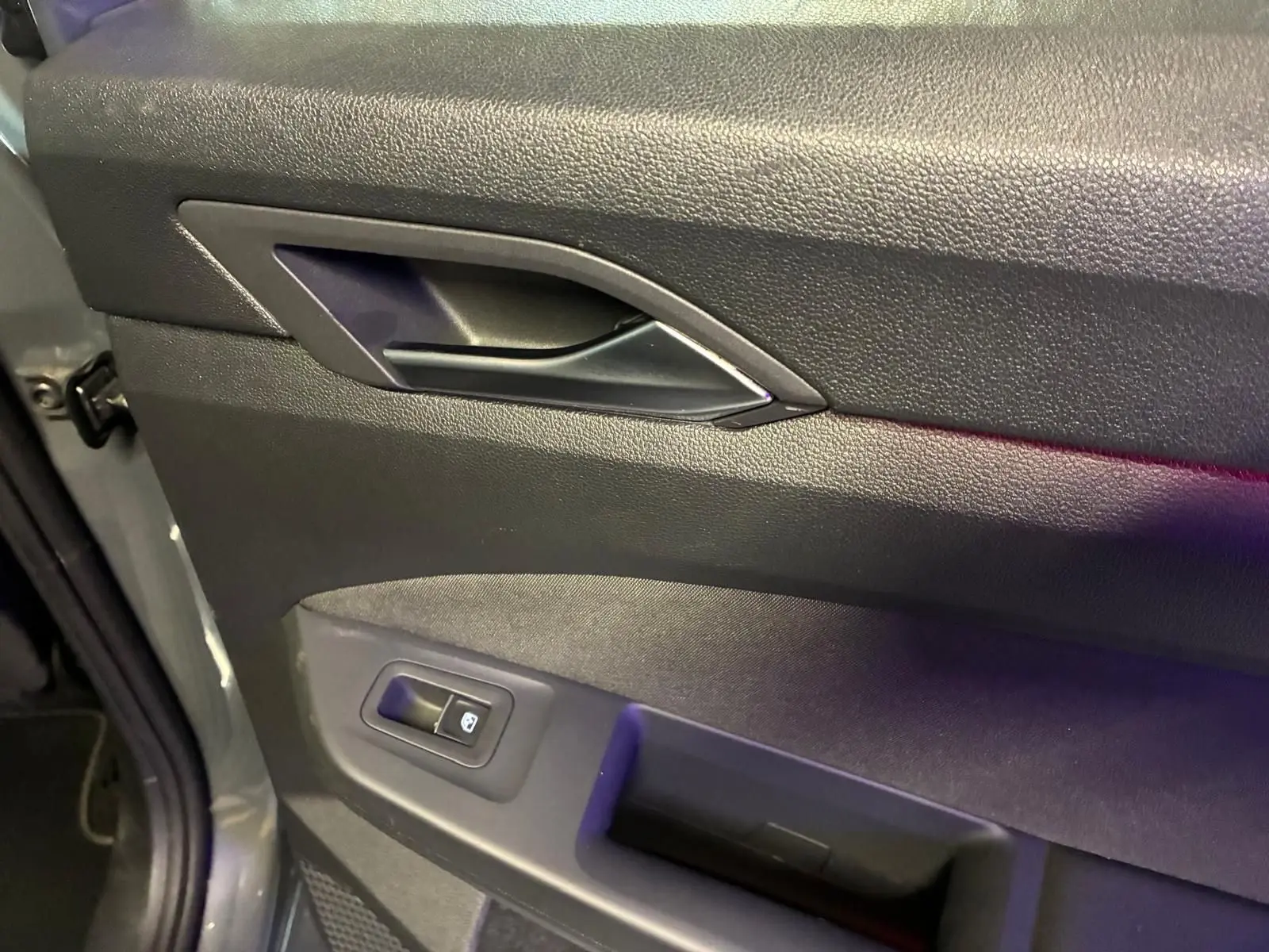 Gros plan sur la porte intérieure côté conducteur d'une Volkswagen Golf gris 1.5 eTSI 130 DSG7 avec bouton de verrouillage.