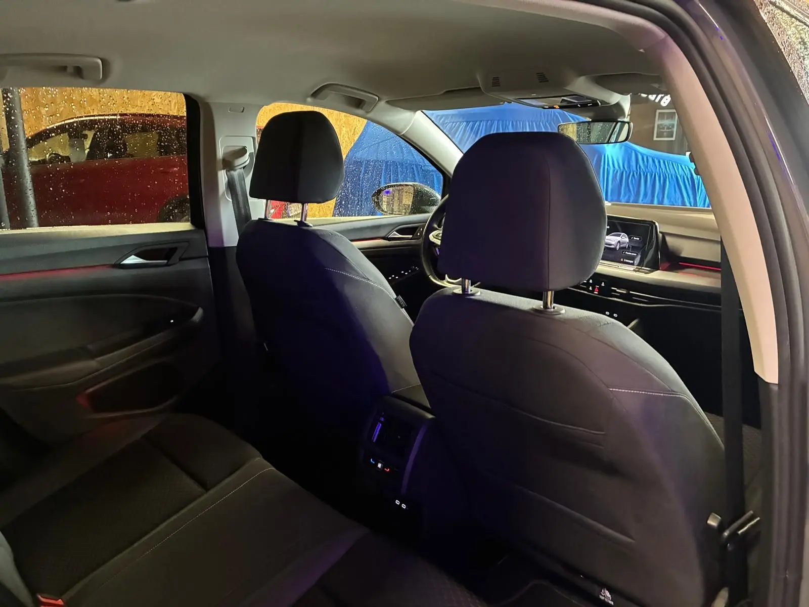 Vue intérieure arrière de la Volkswagen Golf 1.5 eTSI 130 DSG7 Active 2022, sièges tissu noir et tableau de bord visible.