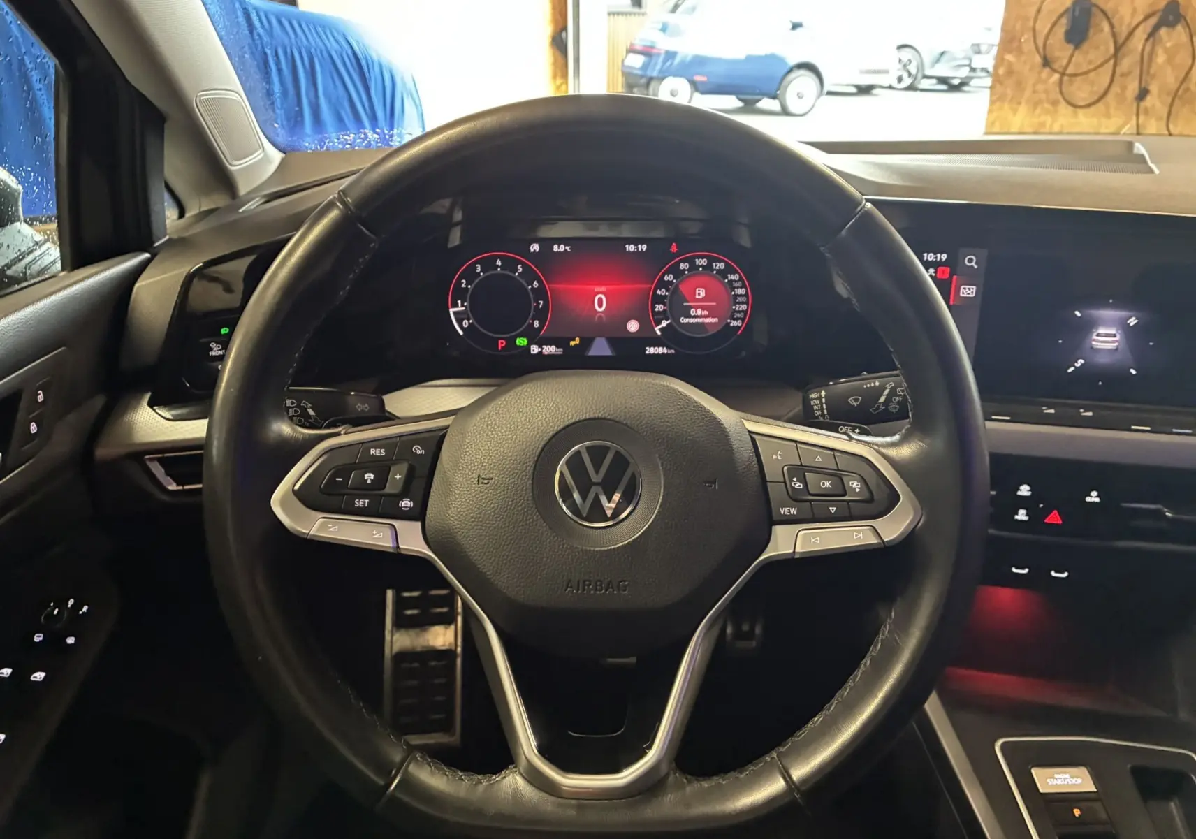 Vue centrée sur le volant noir de la Volkswagen Golf 1.5 eTSI 130 DSG7 Active 2022 avec tableau de bord numérique allumé.