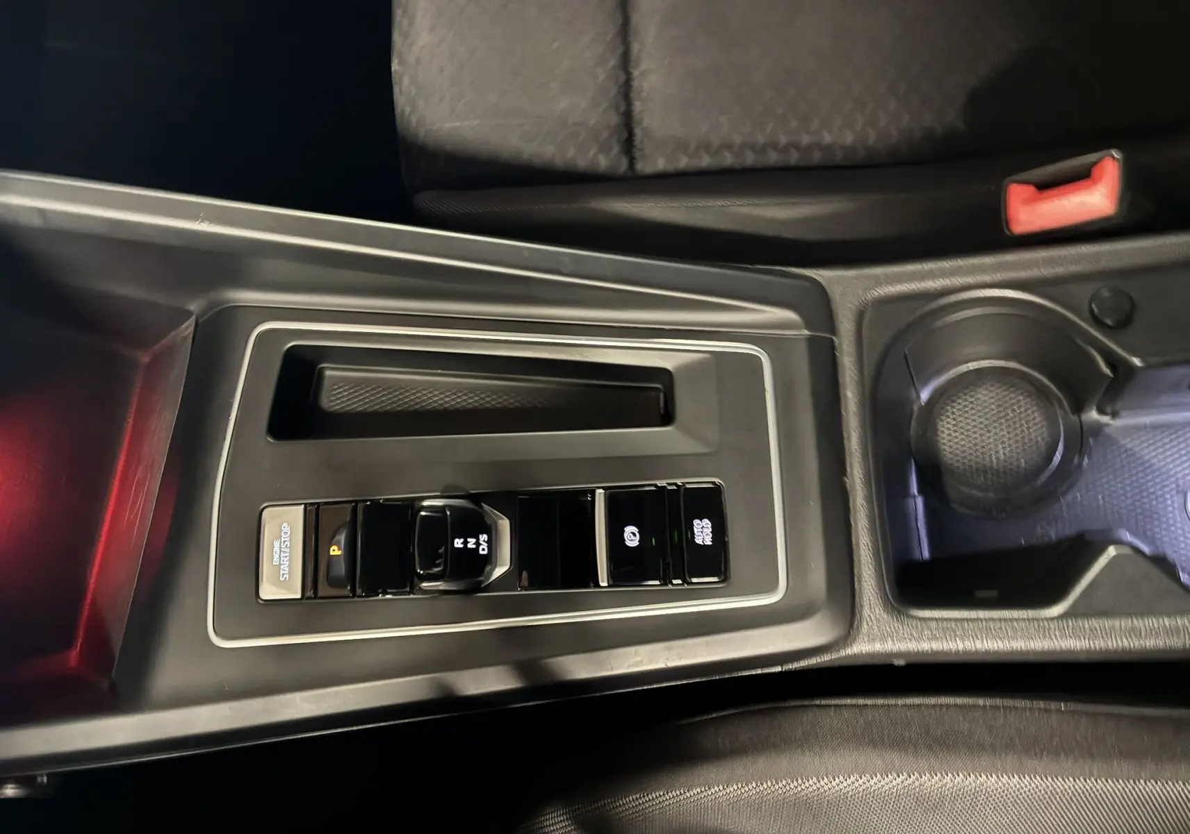 Vue rapprochée de la console centrale noire de la Volkswagen Golf 1.5 eTSI 130 DSG7 avec sélecteur de vitesse électronique et porte-gobelet.