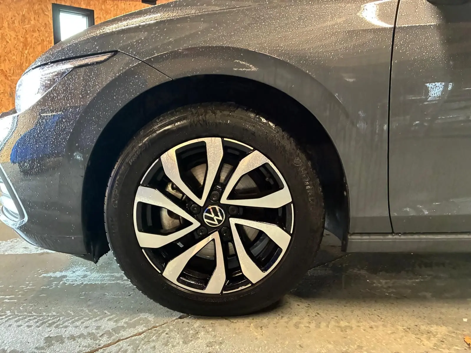 Gros plan sur la roue avant gauche d'une Volkswagen Golf 1.5 eTSI 130 gris 2022 avec jante alliage bicolore.