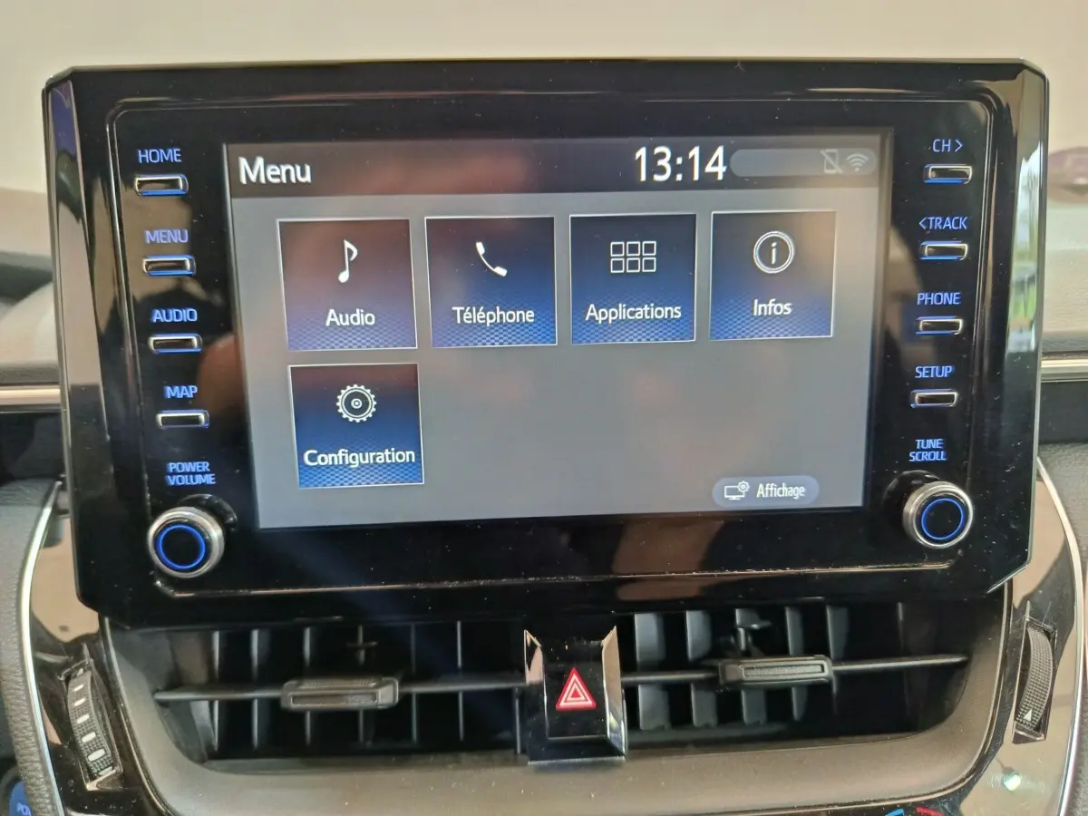 Écran tactile central de la Toyota Corolla Hybride 122h Active 2020 avec menu principal et commandes autour.
