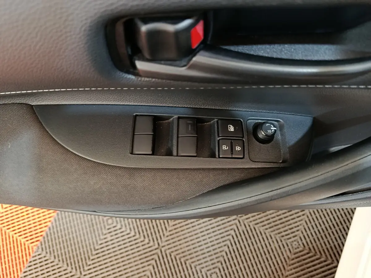 Gros plan sur la commande des vitres et rétroviseurs côté conducteur de la Toyota Corolla hybride blanche 2020.