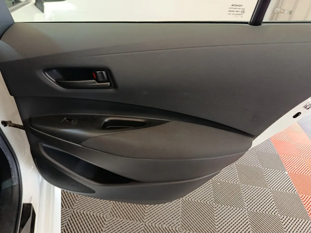 Vue intérieure de la porte arrière gauche noire de la Toyota Corolla Hybride 122h Active blanche de 2020.
