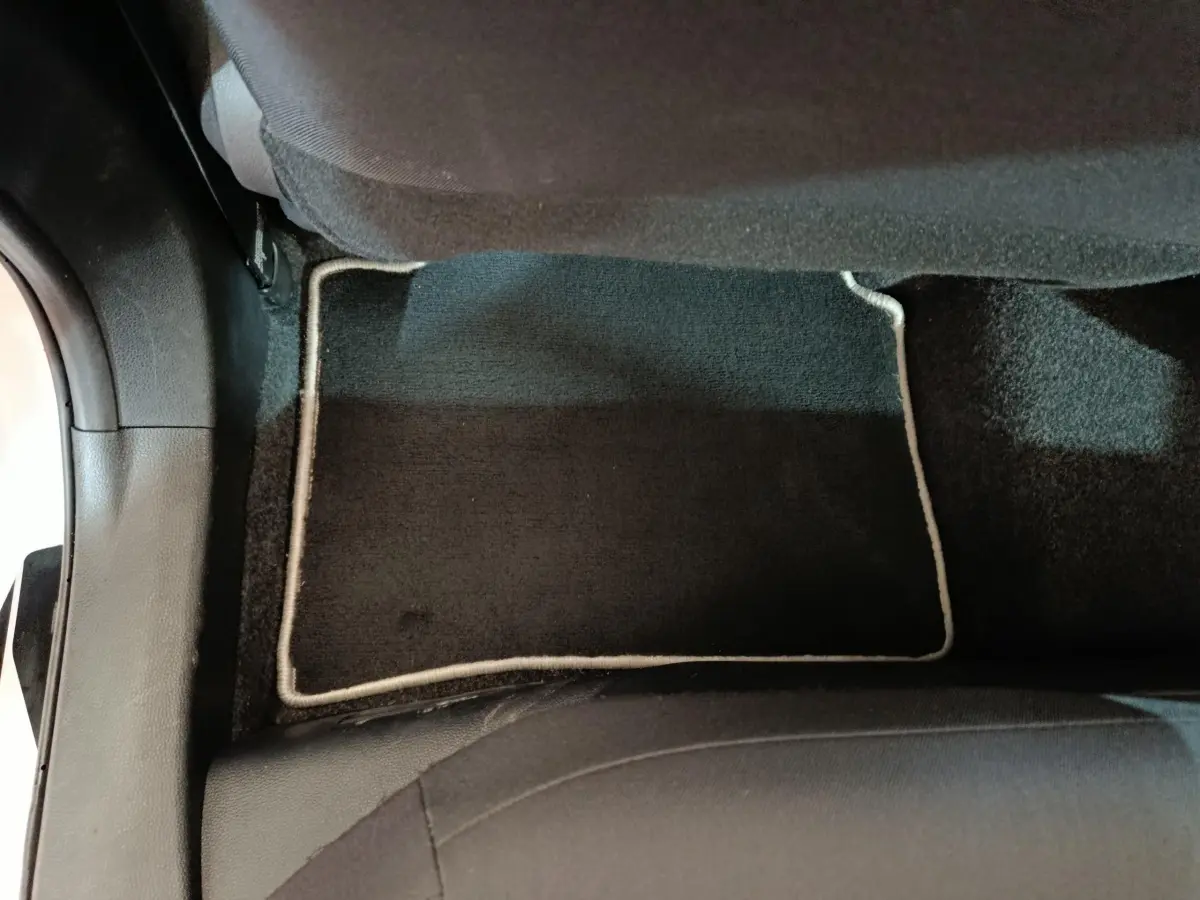 Vue rapprochée du tapis de sol noir avec bordure claire à l'arrière côté droit d'une Toyota Corolla Hybride blanche 2020.