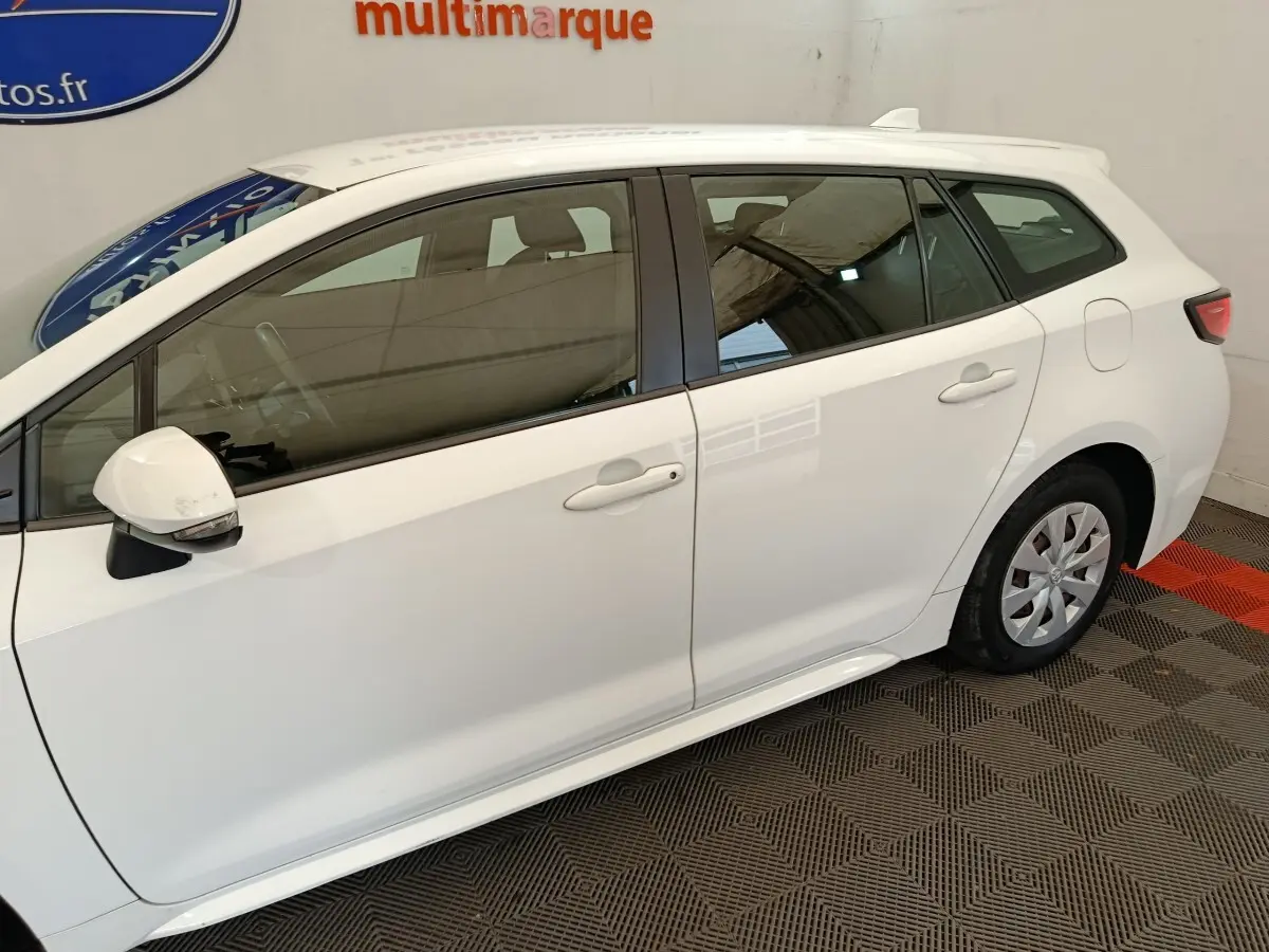 Profil droit d'une Toyota Corolla Hybride 122h Active blanche, avec rétroviseur blanc et jantes acier visibles.