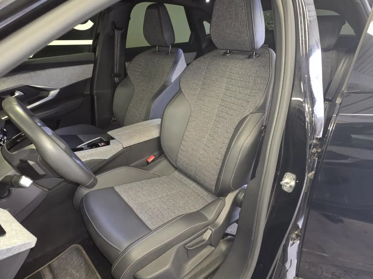 Vue intérieure côté conducteur du Peugeot 3008 noir 2025, sièges tissu gris et cuir noir avec console centrale assortie.