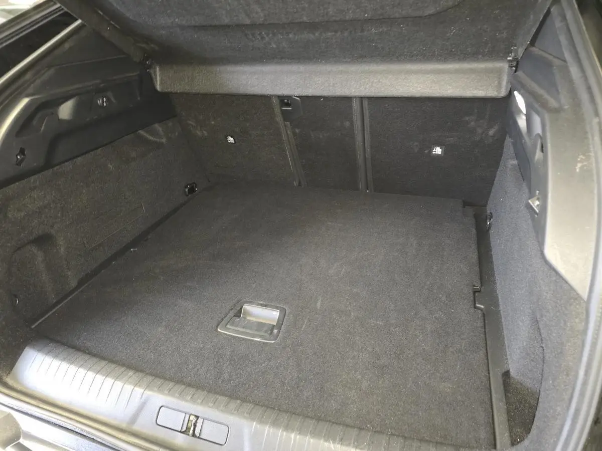 Coffre spacieux noir du Peugeot 3008 1.2i Hybrid 2025 vu de l'arrière avec plancher plat et habillage tissu.
