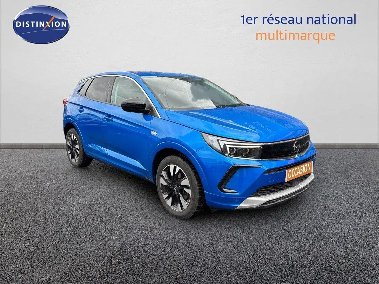 Opel Grandland 2023 bleu Spektrum métal en 3/4 avant droit avec calandre noire et jantes bicolores.