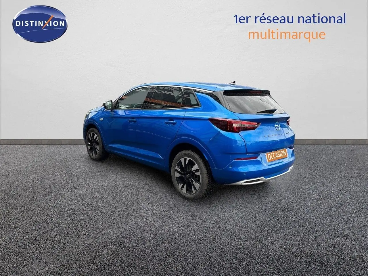 Vue 3/4 arrière droite d'un Opel Grandland bleu Spektrum métal avec jantes noires sur fond neutre.