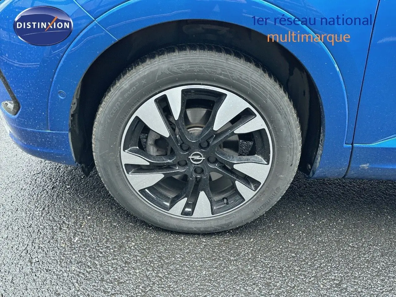 Gros plan sur la roue avant gauche de l'Opel Grandland bleu Spektrum Metal avec jante alliage bicolore.