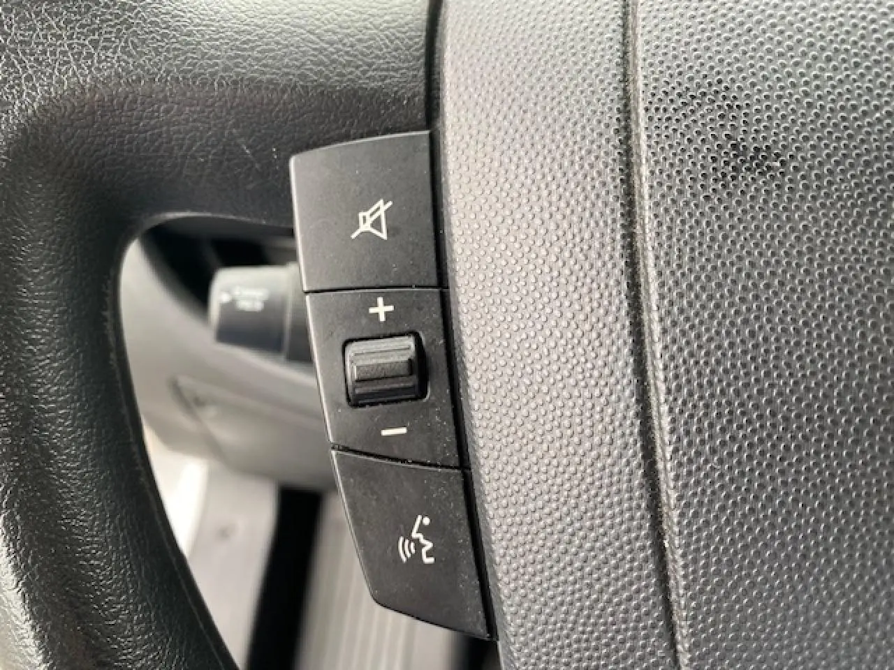 Gros plan sur les commandes audio et vocales au volant noir du fourgon blanc Opel Movano 2023.