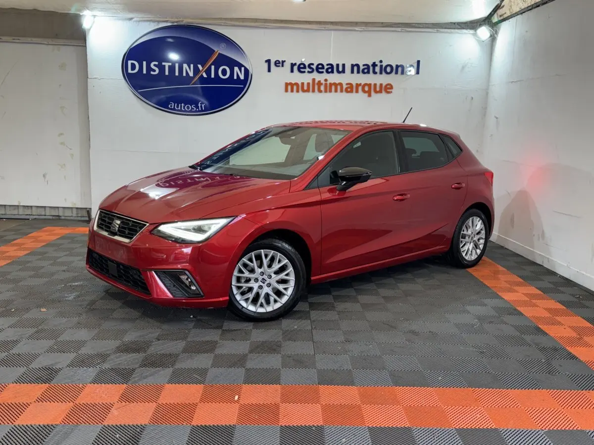 SEAT Ibiza 1.0 TSI 110 FR rouge vue 3/4 avant droit en intérieur sur sol noir et orange.