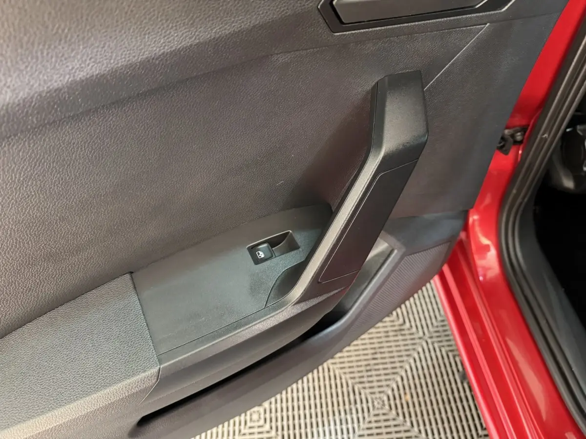 Gros plan sur la porte avant gauche rouge d'une SEAT Ibiza 1.0 TSI 110 FR avec bouton de verrouillage centralisé.