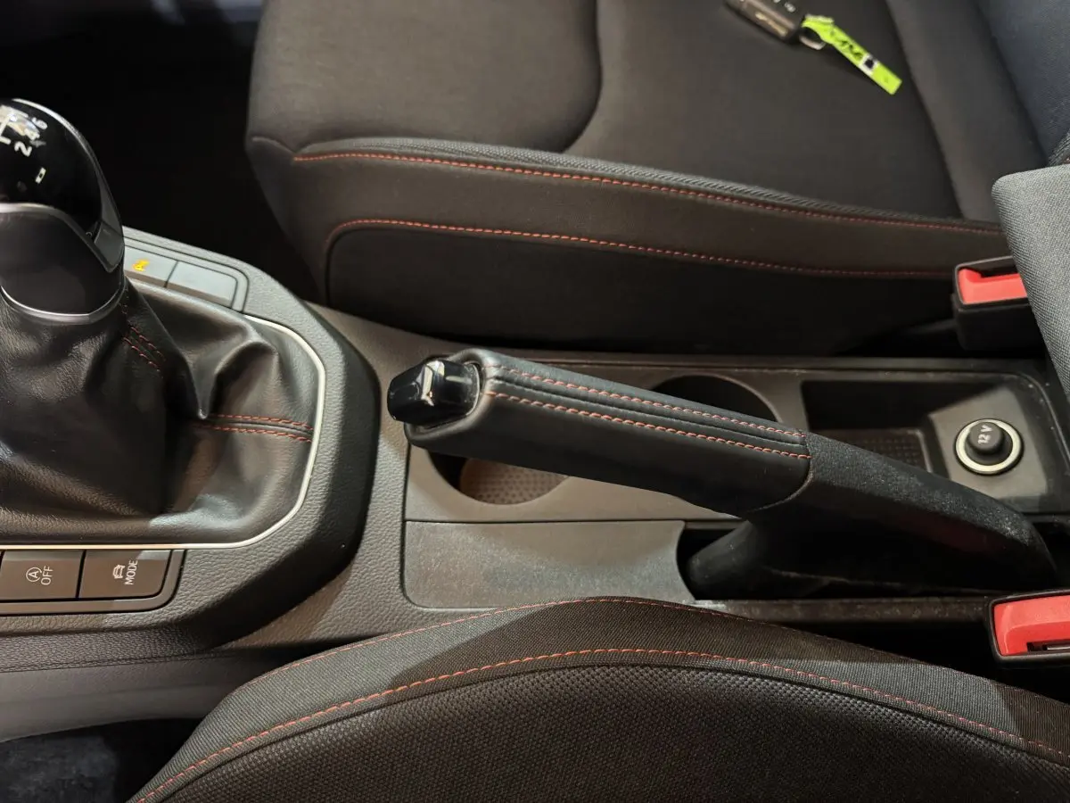 Gros plan intérieur sur frein à main et levier de vitesse manuelle avec surpiqûres rouges dans une SEAT Ibiza rouge 2024.