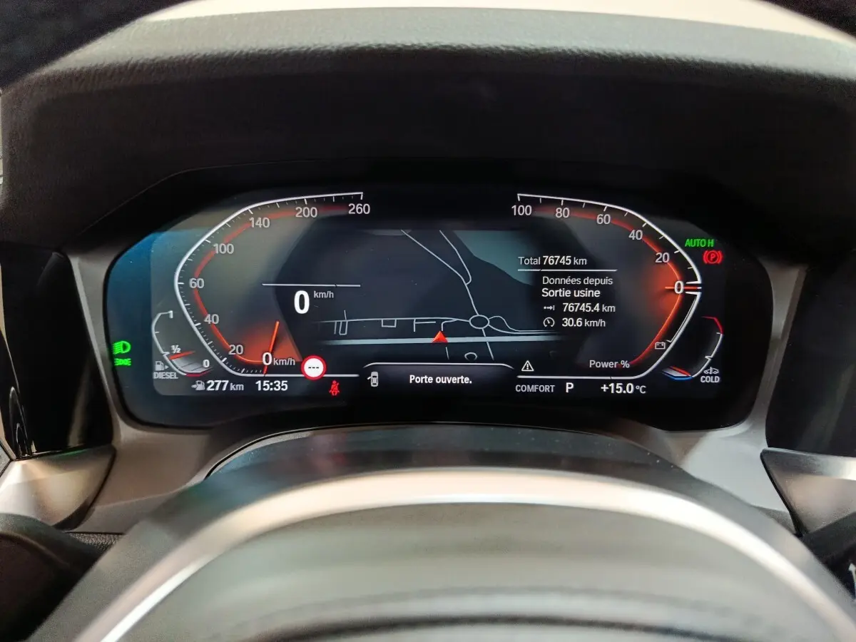 Vue rapprochée du tableau de bord numérique de la BMW Série 3 318d gris clair, affichant la vitesse et la navigation.