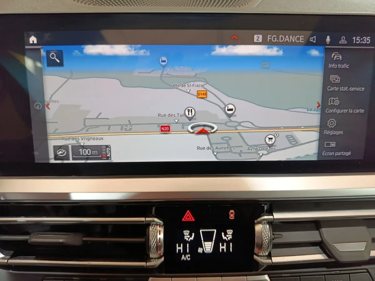 Gros plan sur l’écran tactile central et la console de climatisation d’une BMW Série 3 gris clair, vue intérieure.