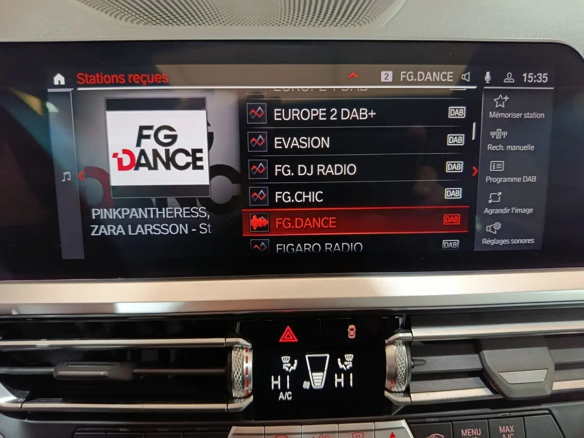 Écran tactile central de la BMW Série 3 318d 2022 affichant les stations radio DAB, avec commandes climatisation en dessous.